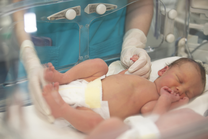 Photo shows a doctor holding the hand of a baby in a hospital bed/Getty Images