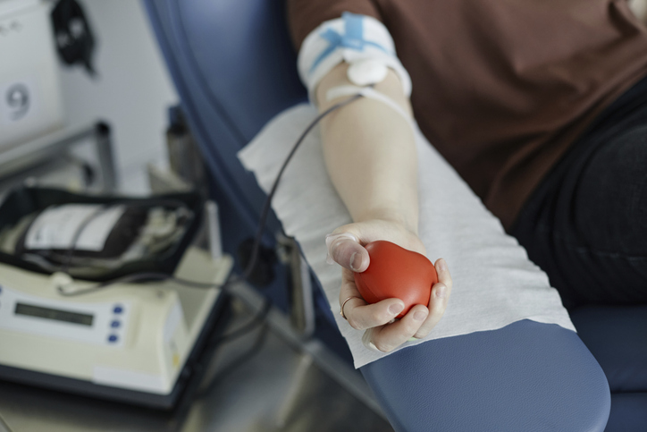 Photo shows the hand of a woman holding a soft ball donating blood/Getty Images