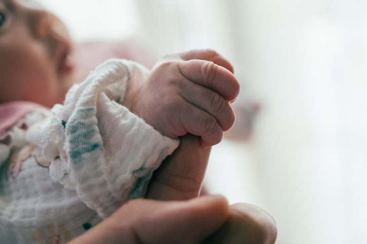 Photo shows a newborn baby holding an adult's finger/Getty Images
