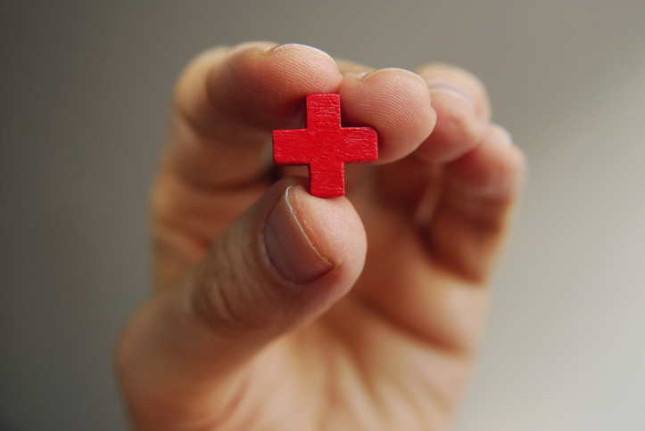 Photo shows male fingers holding a little red cross/Getty Images