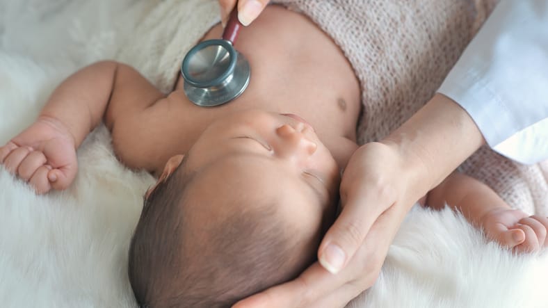 Photo shows a doctor examining a baby with a stethoscope/Getty Images