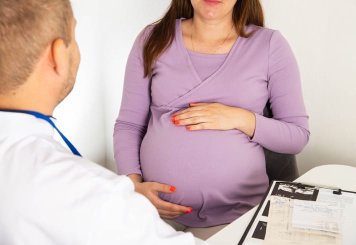 Photo shows a pregnant woman speaking with her doctor/Getty Images