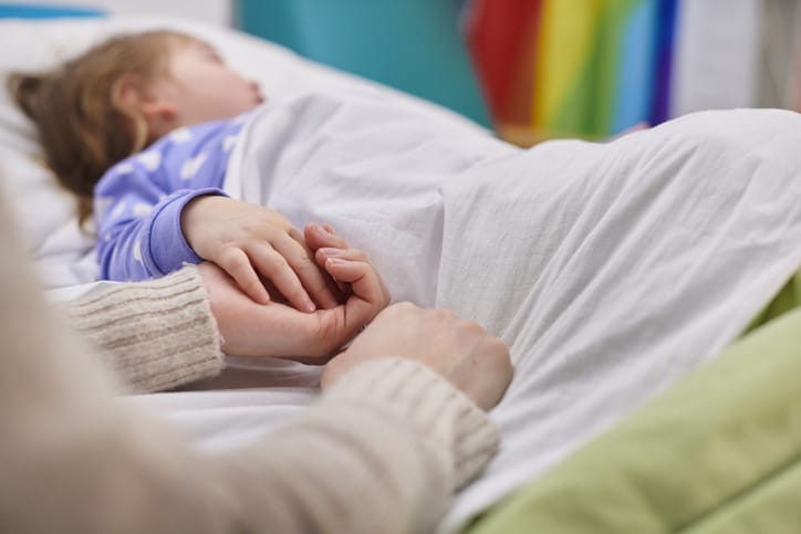 Photo shows a mother and daughter holding hands in children's hospital/Getty Images