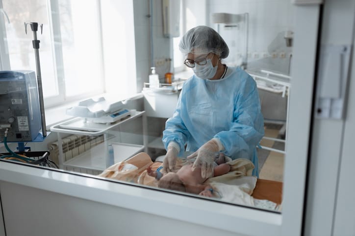 Photo shows a doctor examining an infant in the NICU/Getty Images