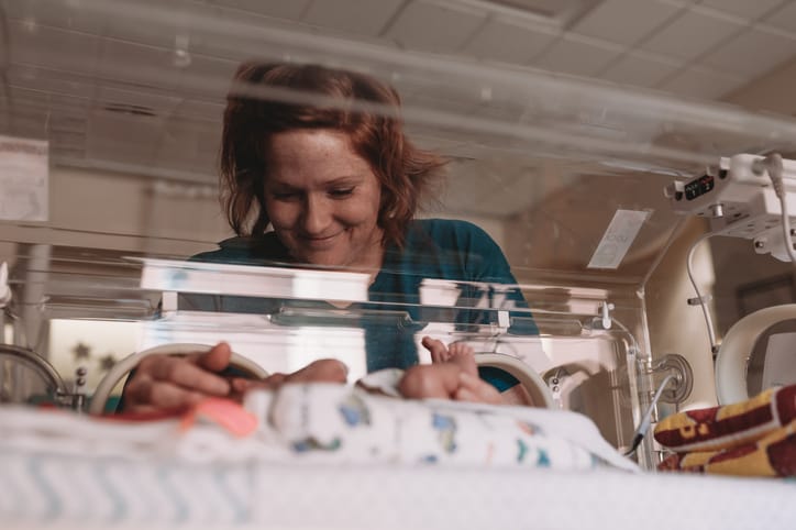 Photo shows a woman caring for a baby in the NICU/Getty Images