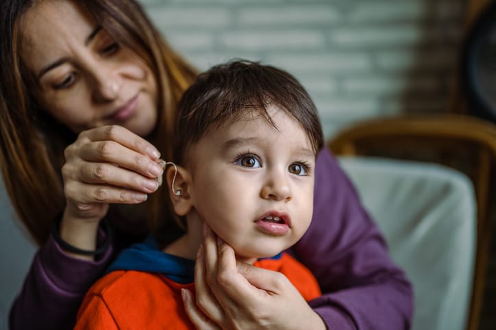 Photo shows a mother helping her son with his hearing aid/Getty Images