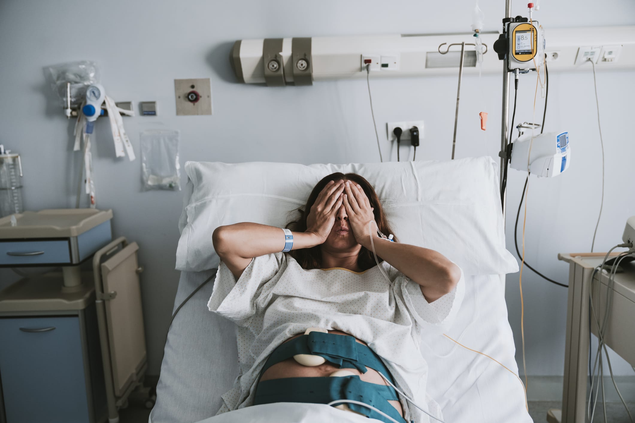 Photo of stressed pregnant woman lying on bed in hospital