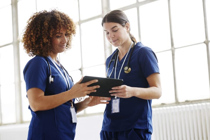 Photo shows two healthcare professionals looking at a tablet together/Getty Images