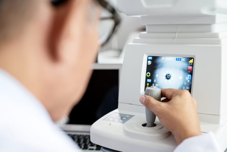 Photo shows an ophthalmologist using a modern eye test equipment tool to perform a vision exam/Getty Images