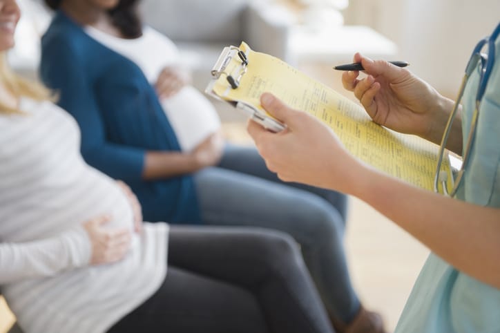Photo shows a nurse taking notes with two pregnant women sitting nearby/Getty Images