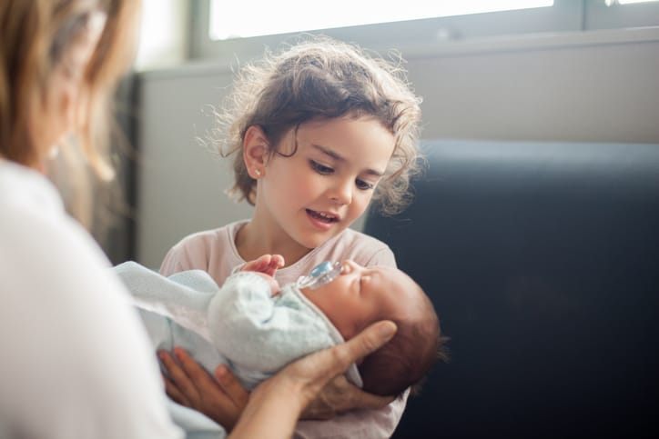 Photo shows a child meeting her little sibling for the first time/Getty Images