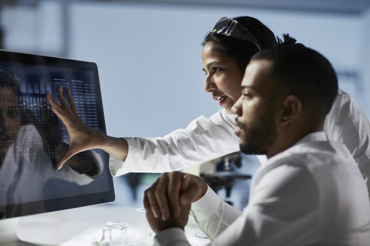 Photo shows two scientists working on a computer in a lab/Getty Images