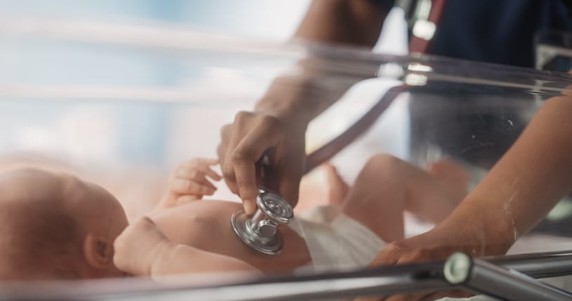 Photo shows a doctor listening to a newborn's heartbeat with a stethoscope in the NICU/Getty Images