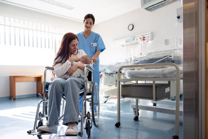 Photo shows a nurse pushing a woman with a newborn in a wheelchair while leaving the hospital/Getty Images