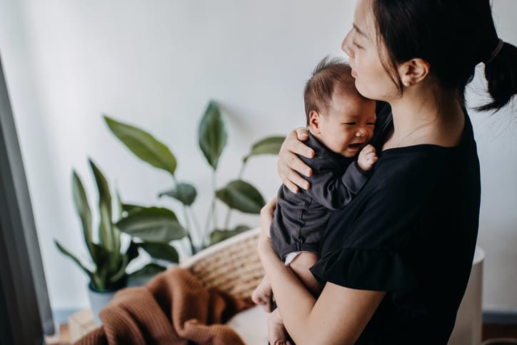 Photo shows a mother comforting her crying infant/Getty Images