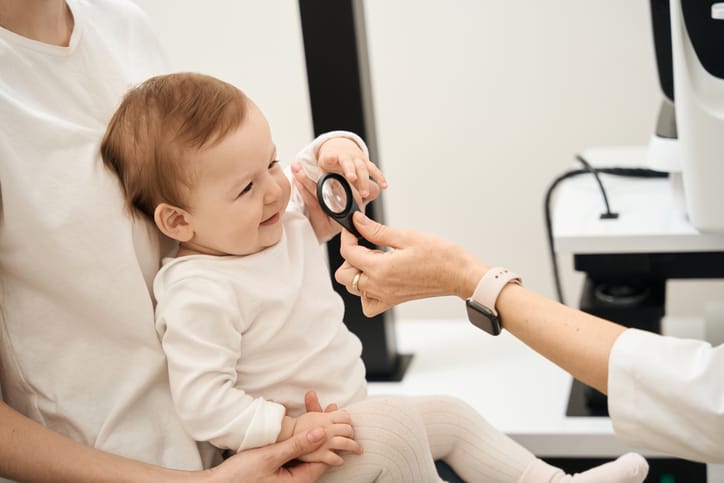 Photo shows a pediatric eye doctor examining a baby's eyes/Getty Images