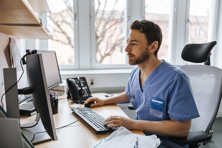 Photo shows a medical provider working on a computer at a medical facility/Getty Images