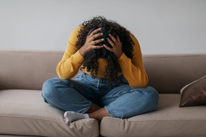 Photo shows a distressed woman sitting on her sofa/Getty Images