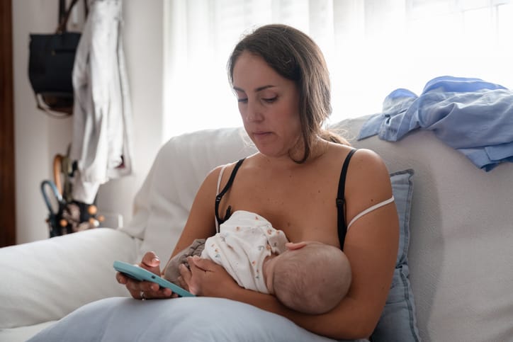 Photo shows a mother breastfeeding her newborn baby while using her mobile phone/Getty Images