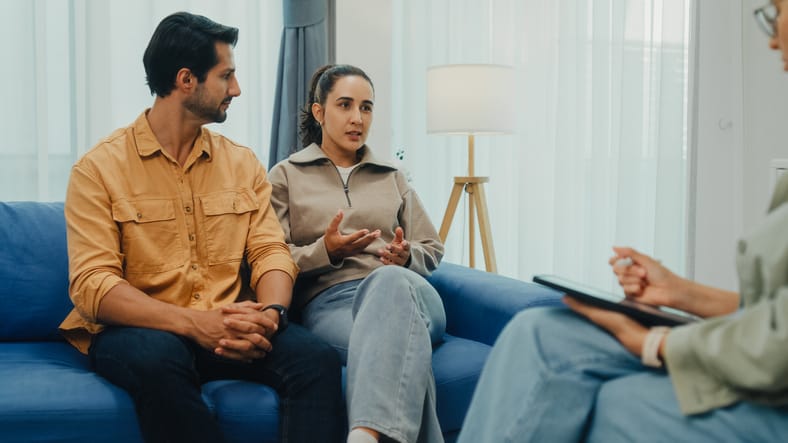 Photo shows a young couple attending a session with a therapist/Getty Images