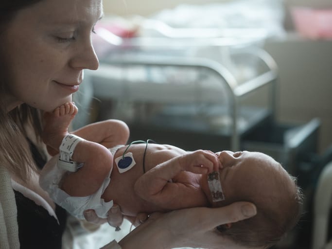 Photo shows a mother holding her newborn baby in a hospital room/Getty Images