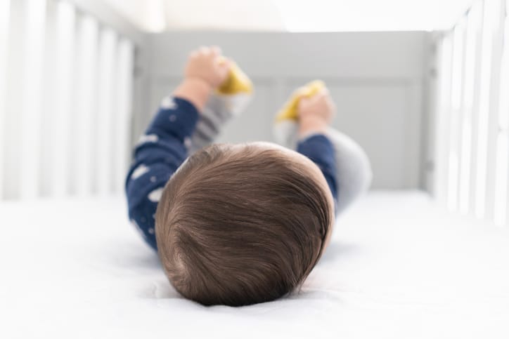 Photo shows a baby playing in its crib/Getty Images