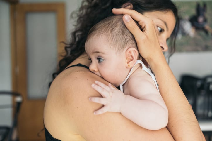 Photo shows a young mother holding her baby at home/Getty Images