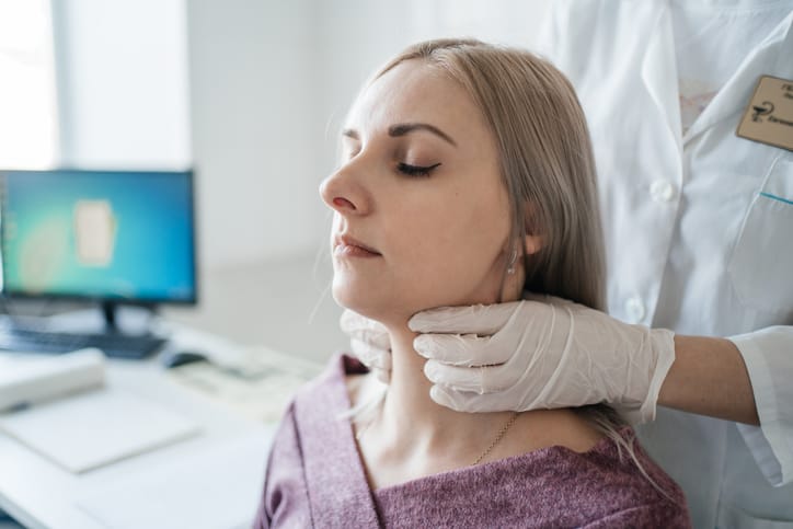 Photo shows a doctor examining a patient's thyroid/Getty Images