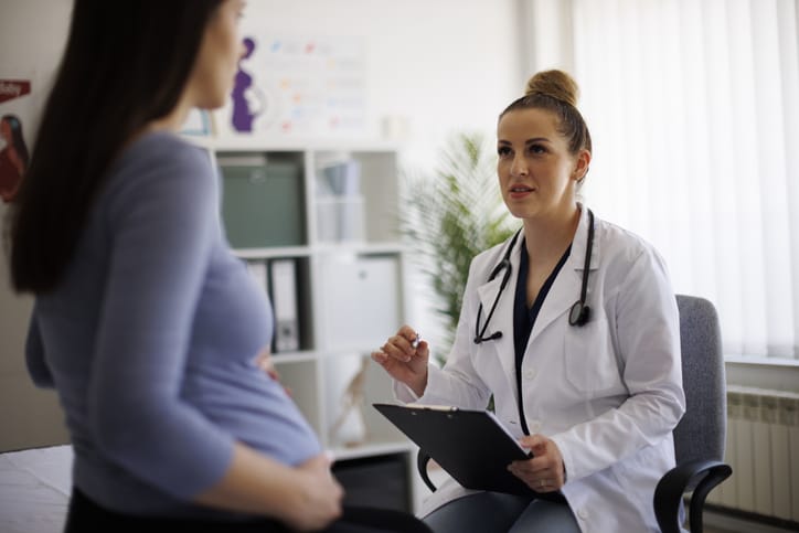 Photo shows a doctor talking to a pregnant patient/Getty Images