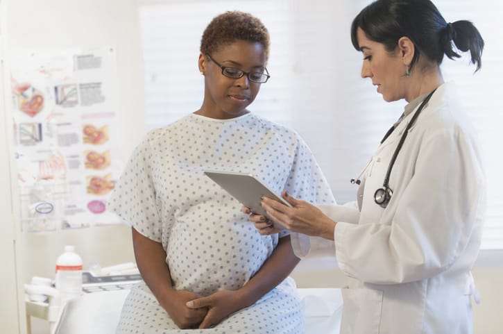 Photo shows a doctor and patient looking at a digital tablet in a hospital/Getty Images