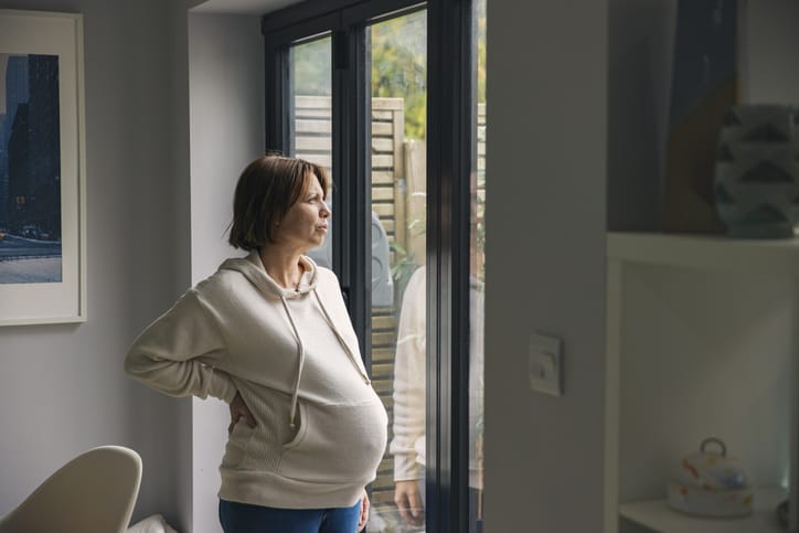 Photo shows a pregnant woman looking out her window/Getty Images/Justin Paget