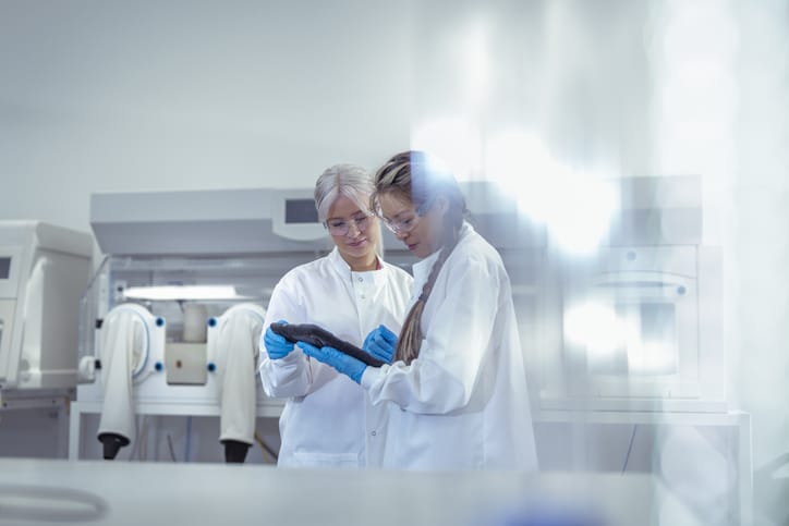 Photo shows female scientists discussing data on digital tablet in microbiology laboratory/Getty Images/Monty Rakusen